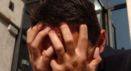 Manager con le mani nei capelli e aziende in ginocchio
