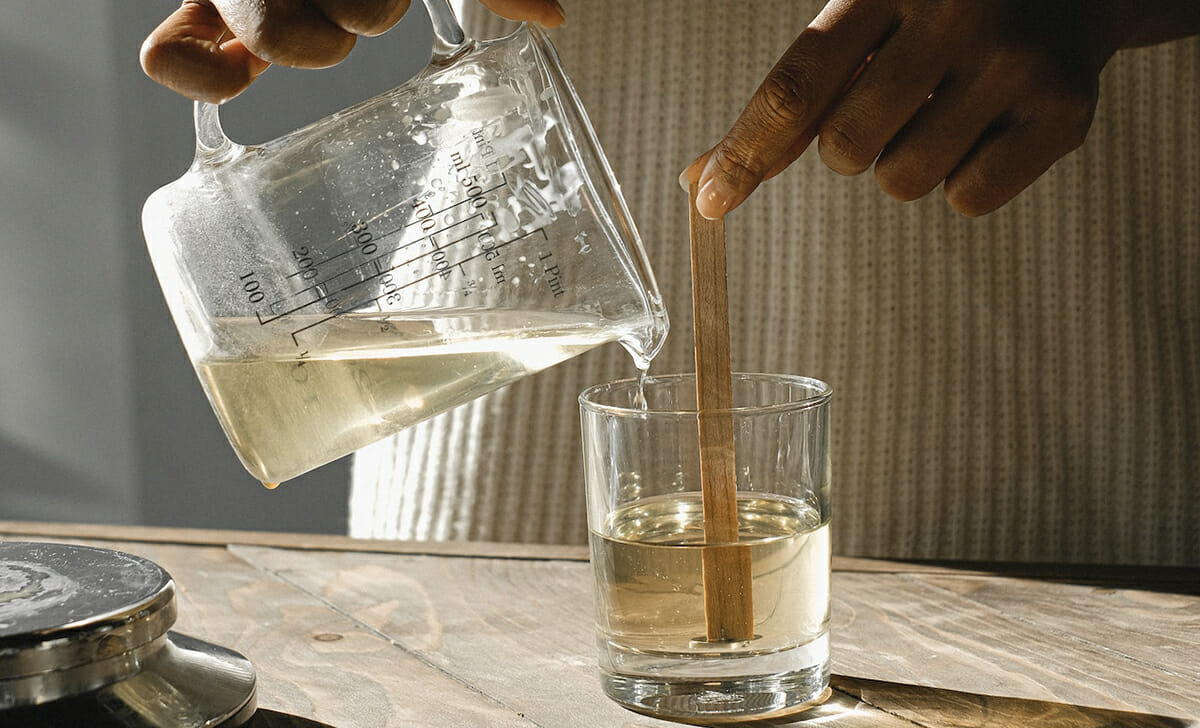 Sciogliere la cera a bagnomaria, aggiungere l'olio essenziale e mescolare