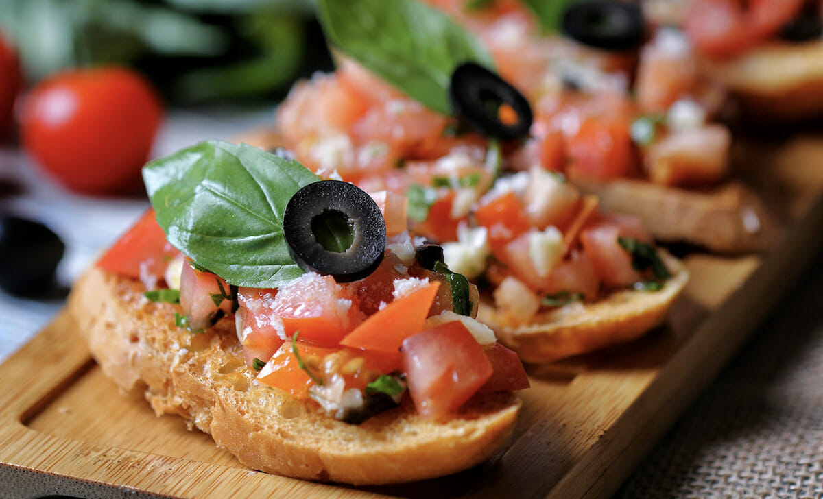 Come antipasto possiamo preparare delle bruschette con pane, pomodori e olive